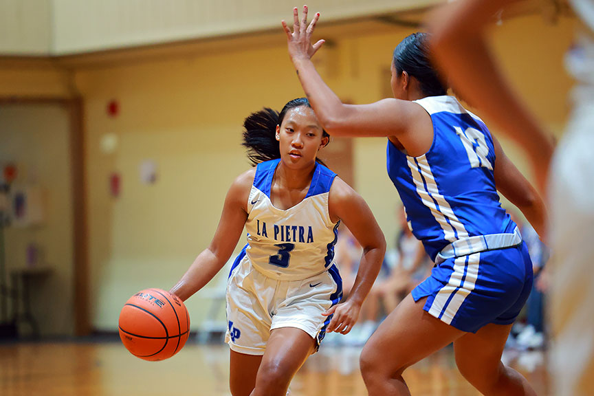 Student playing basketball tries to dribble around the other team.